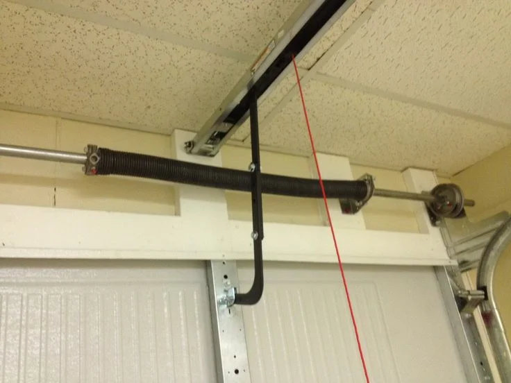 Torsion spring assembly above a garage door being measured in Mason, Ohio